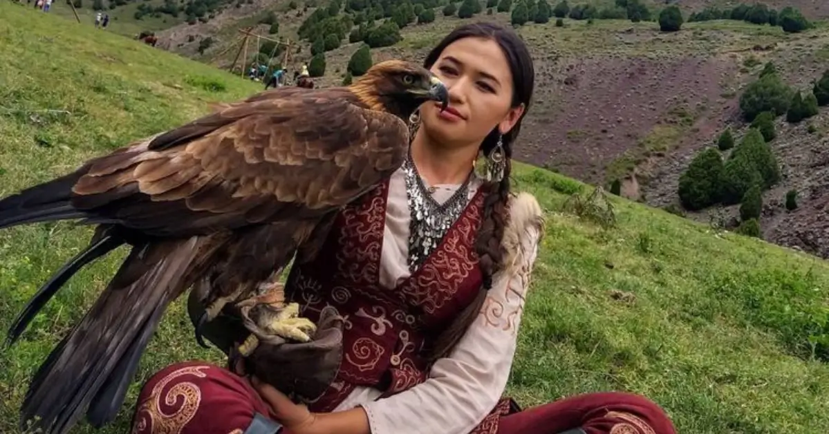 Young Kazakh eagle huntress holding her trained Berkut eagle during a winter festival in Mongolia.