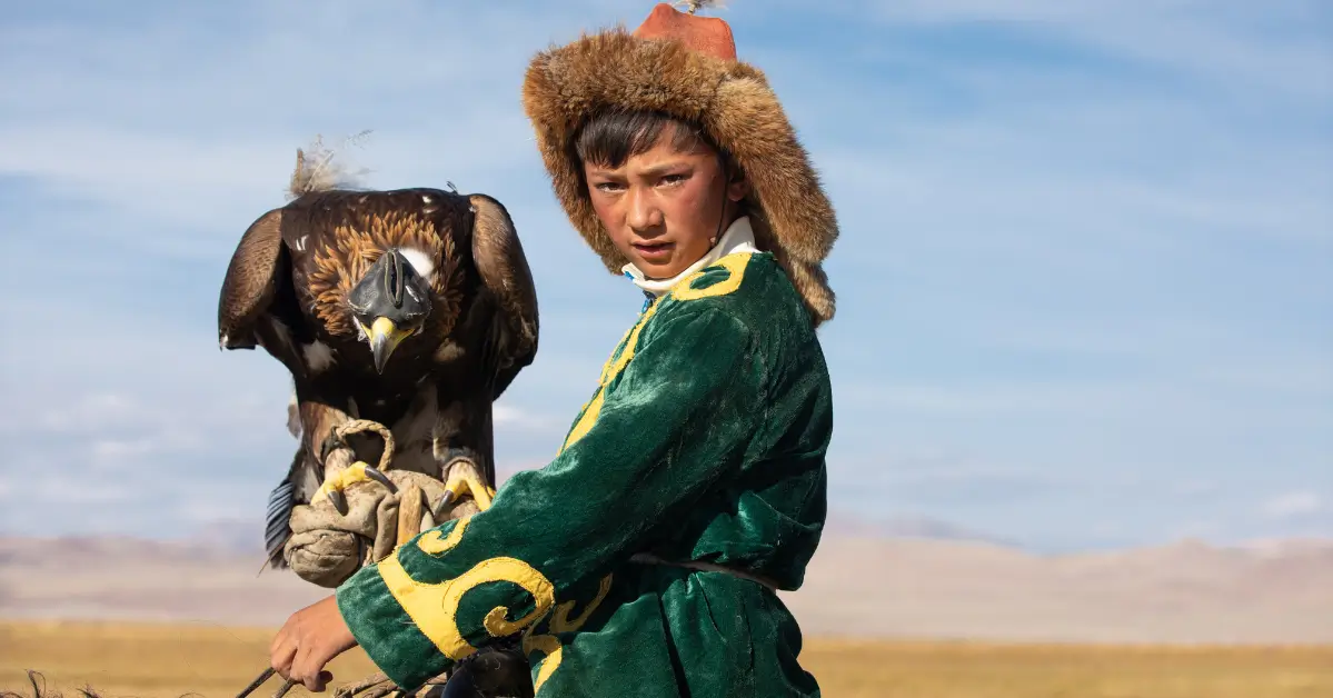 Kazakh hunter sharing a quiet moment with his trained golden eagle inside a winter ger.