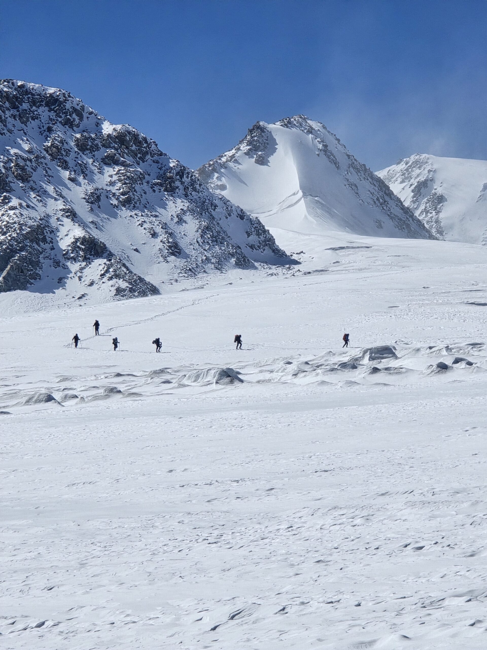 Trekker silhouette ascending Khuiten Peak ridge in the Altai Mountains
