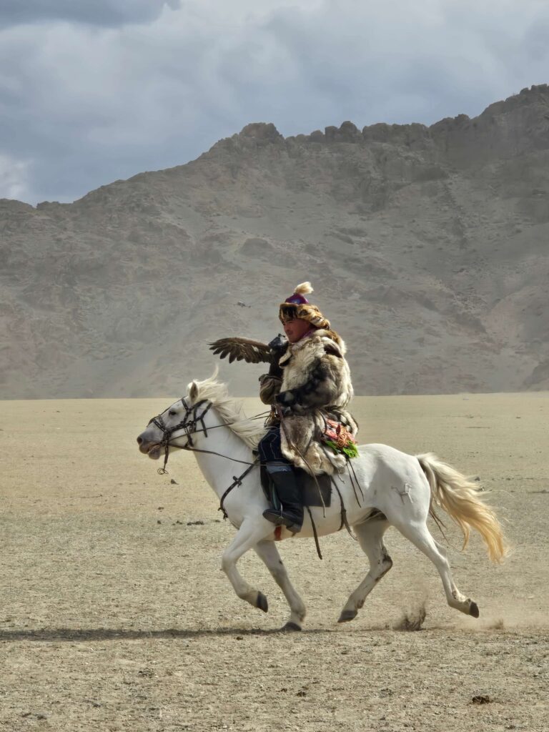 Eagle hunter galloping on white horse with golden eagle wings spread