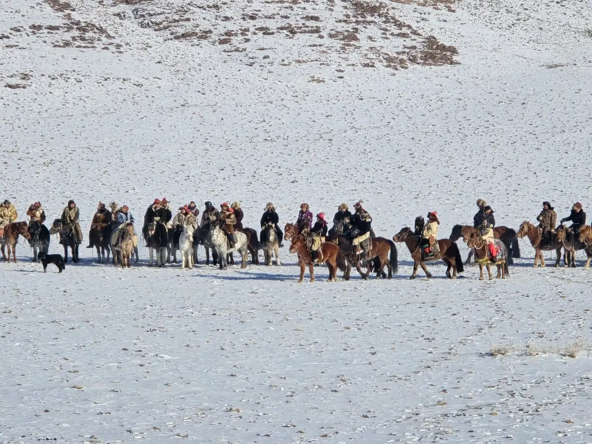 Line of riders and eagle hunters on a snowy plain at the festival